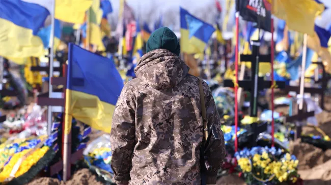 Ukraine war memorial with headstones, flags, and flowers